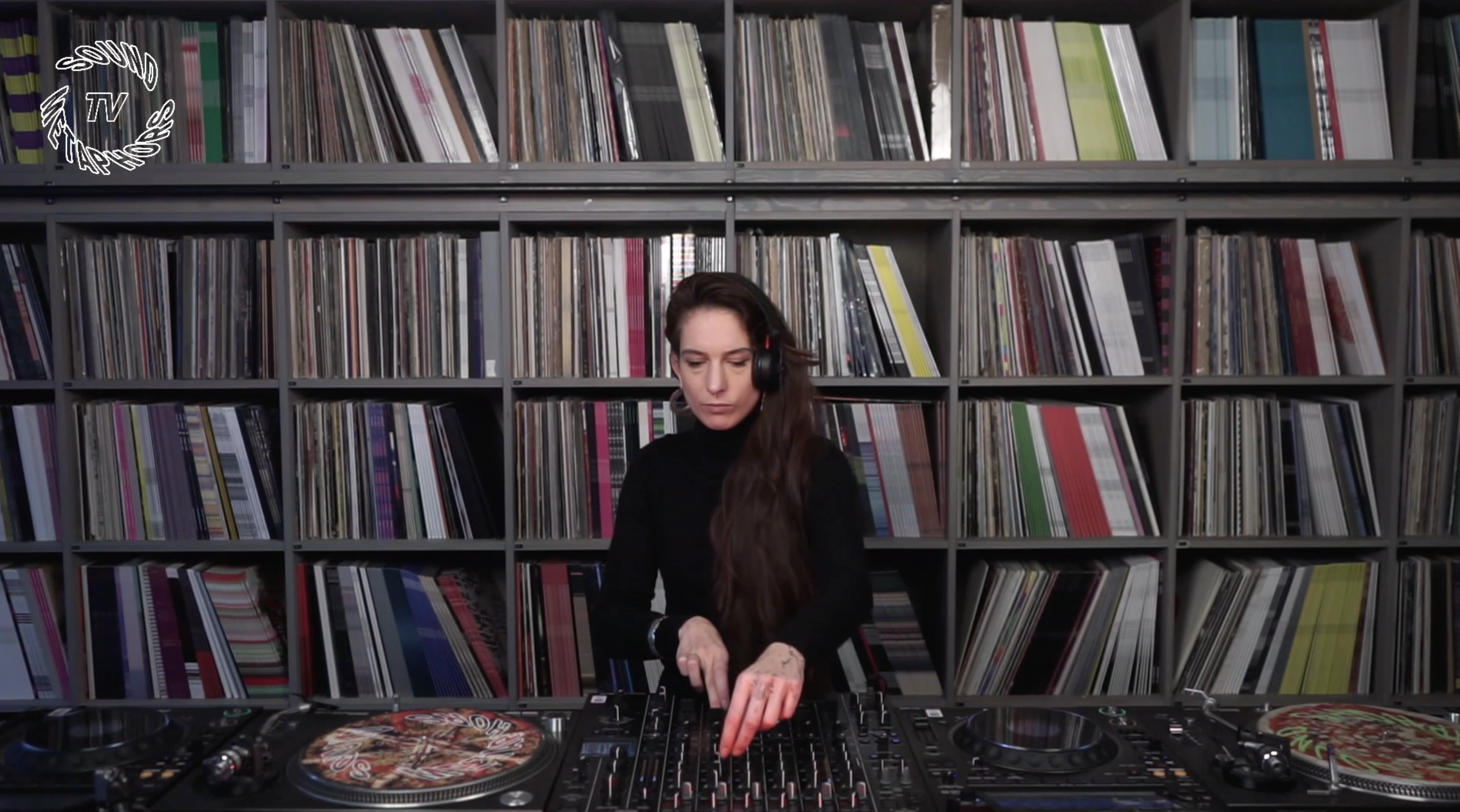 Ninon playing a DJ set in a room lined floor to ceiling with records, for a Sound Metaphor TV session