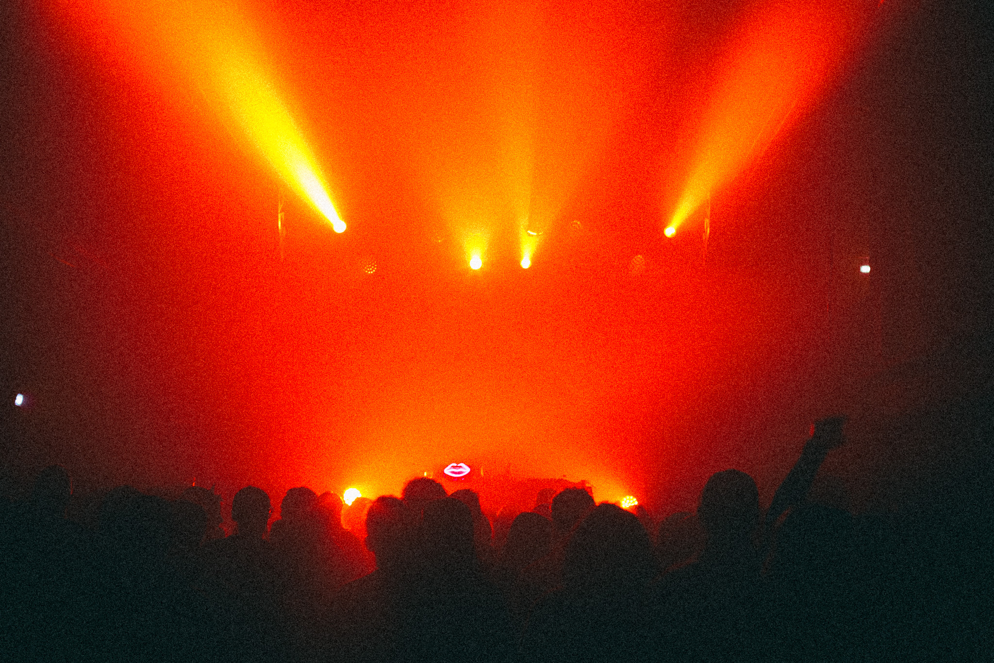 The room at La Station: red beams cutting through haze over a dense crowd, the booth lit at the far end