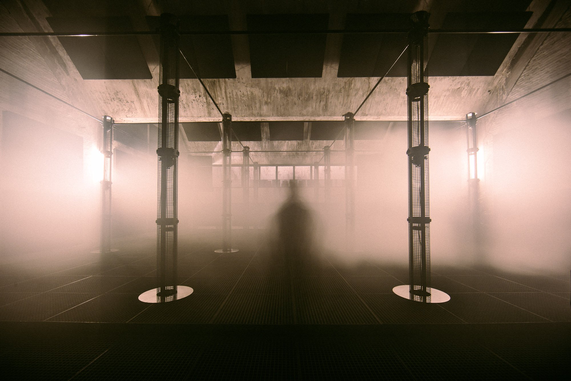 The MONOM studio: a large dark room ringed by the 4DSOUND speaker array on vertical poles
